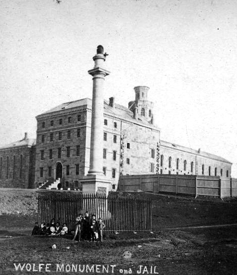 Vue éloignée de la façade et du profil droit de la prison, avec le monument Wolfe.